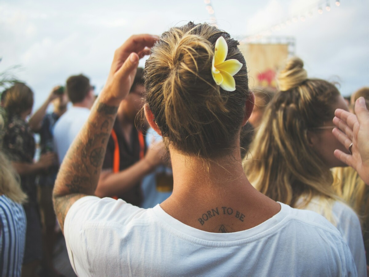 a woman with a yellow flower on her hair and some tattoos on her arm and neck